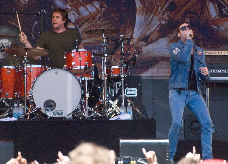 the man is singing to his band while holding his microphone