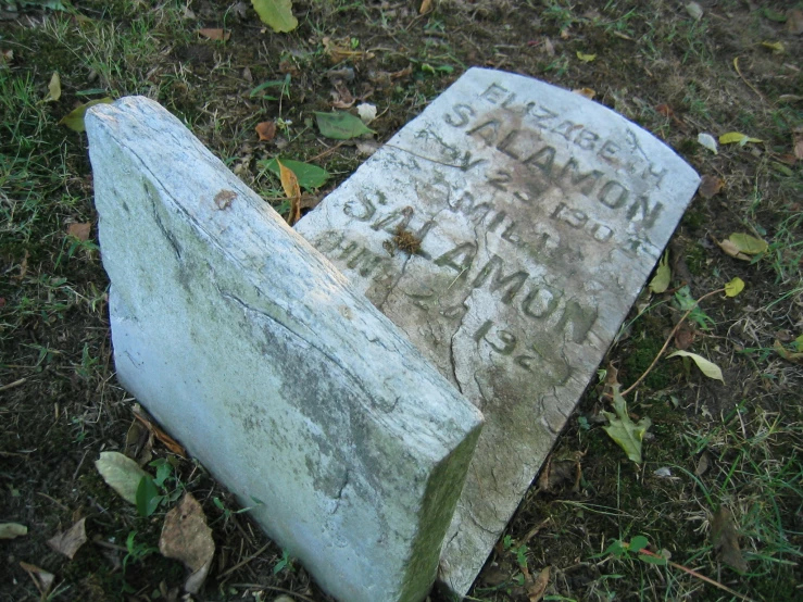 the headstones of two different people are sitting on the ground
