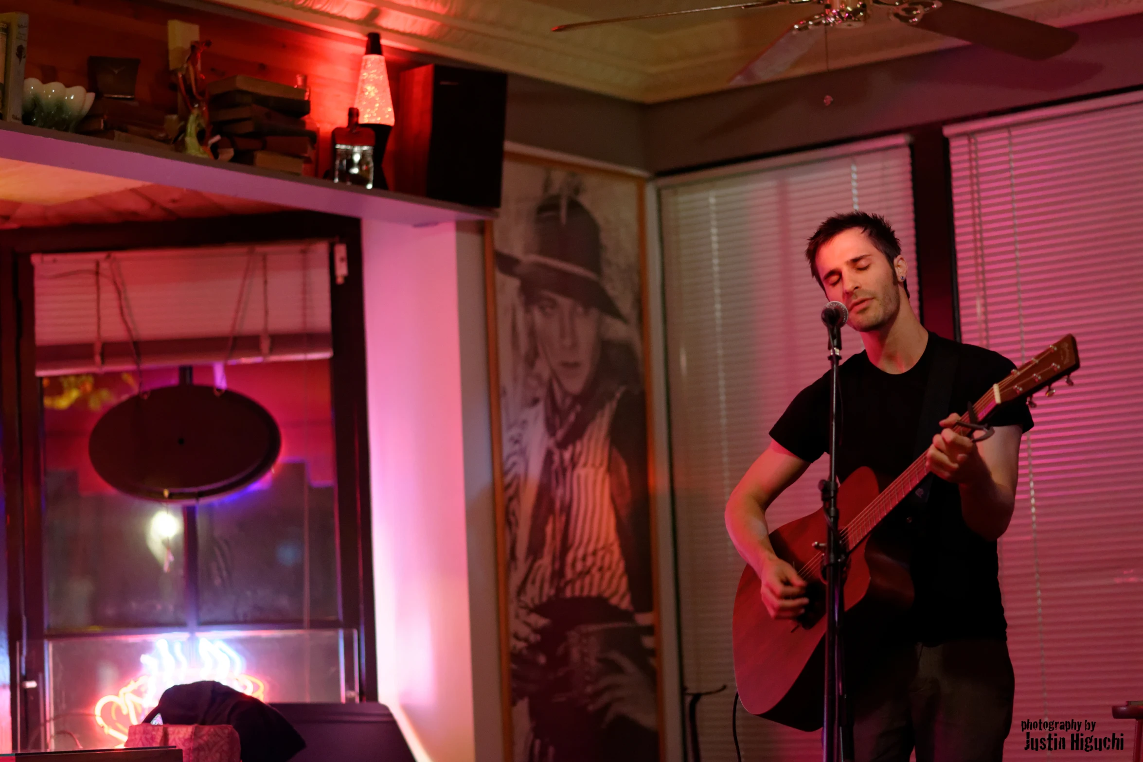 man playing guitar in room with pink lighting