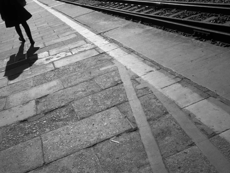 a woman walking down a sidewalk next to a train track