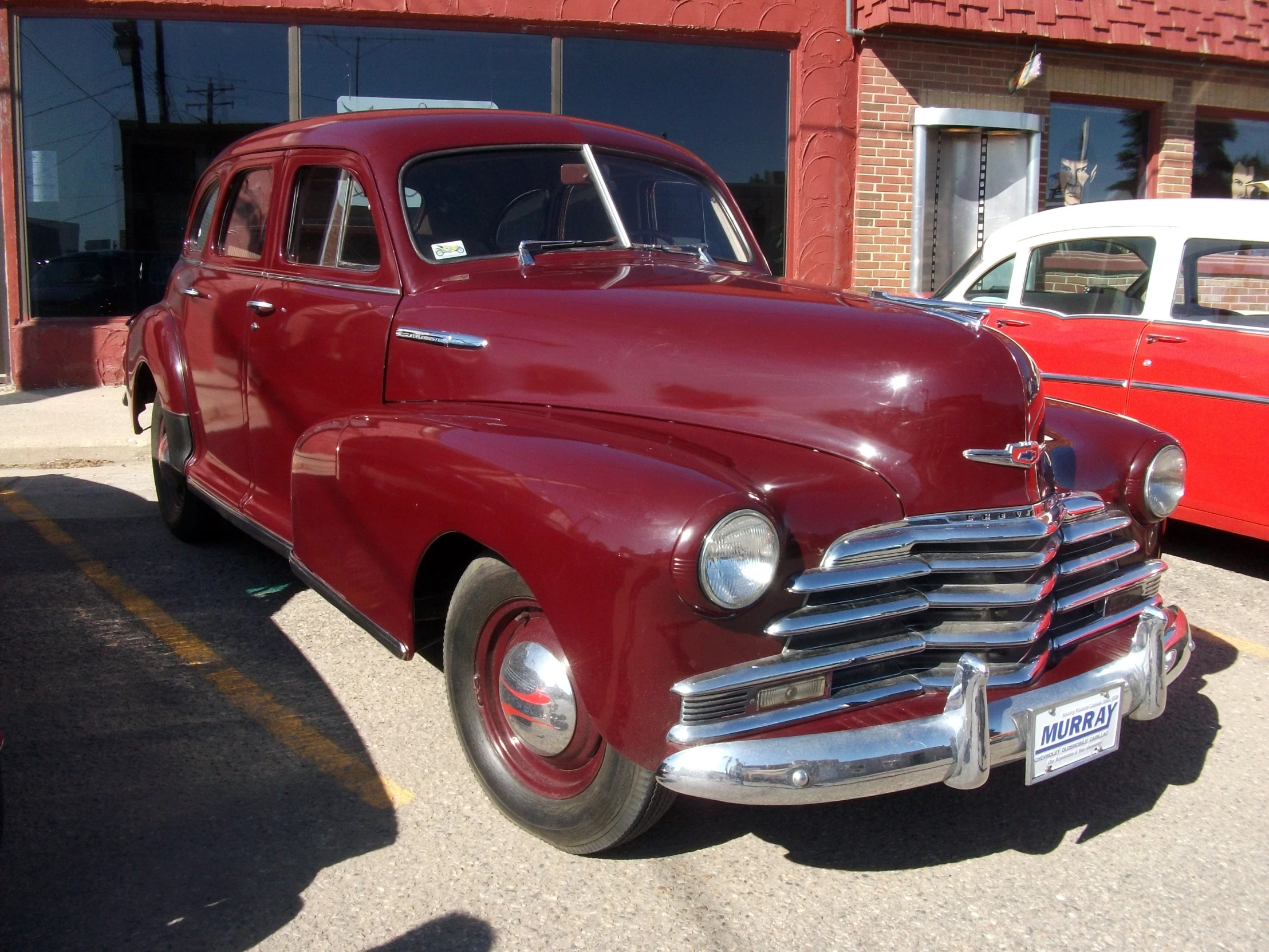 two old cars parked in front of a red building