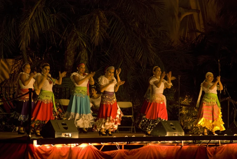 several women in colorful dresses and headdresses on stage