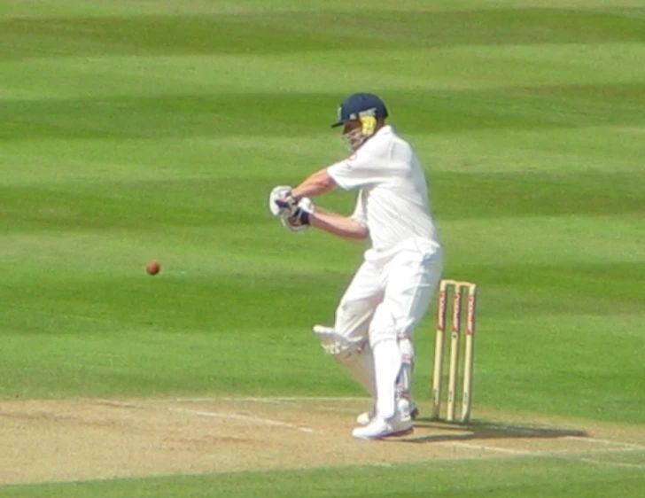a player in white is hitting a ball with a bat