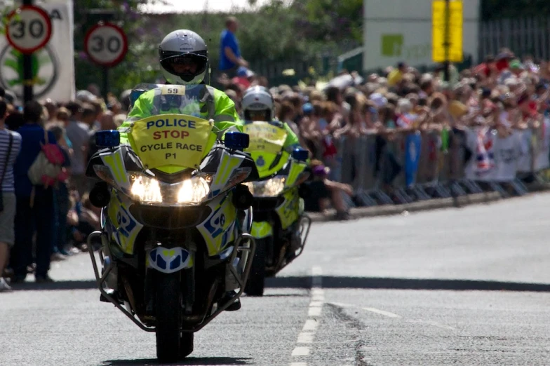 the three police officers are driving motorcycles behind the crowd