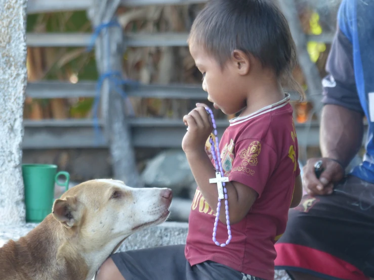 a young child sitting with his dog in a dog pen