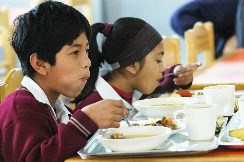 two children eat food at a table