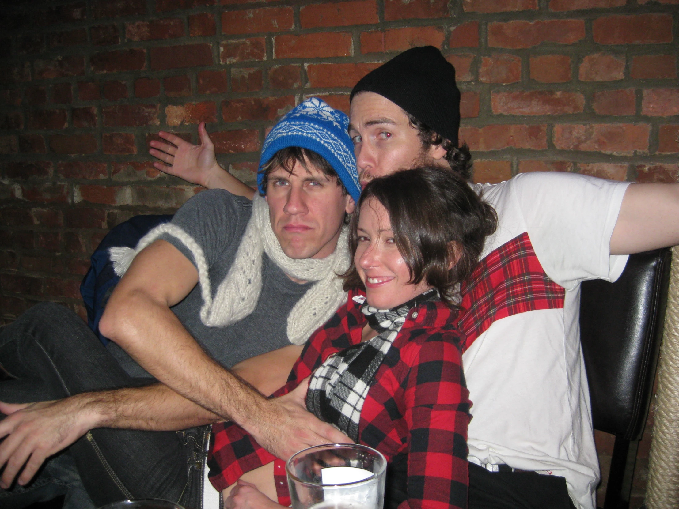 three people sitting together in front of a brick wall