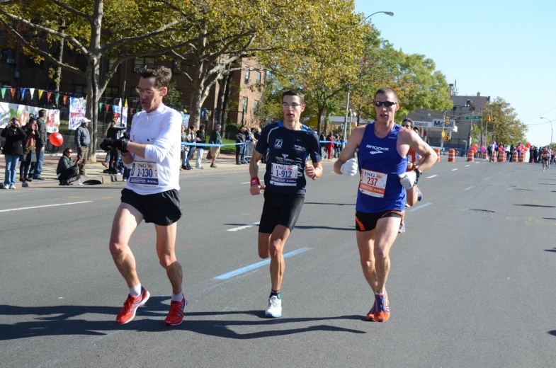 three men running in a marathon down a city street