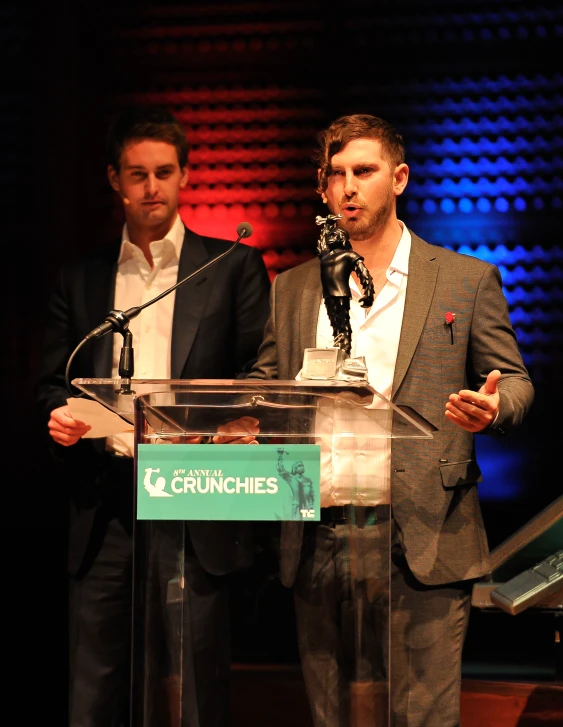 a man in suit and tie speaking at a podium