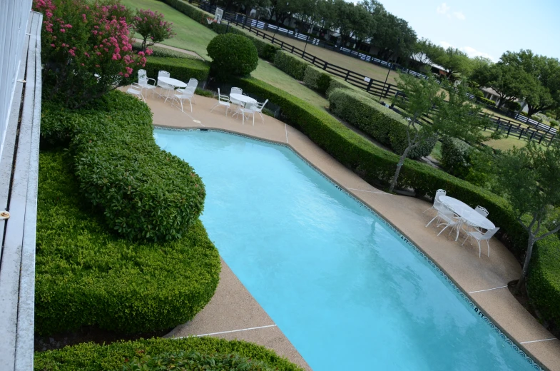 the view of an outdoor swimming pool with chairs