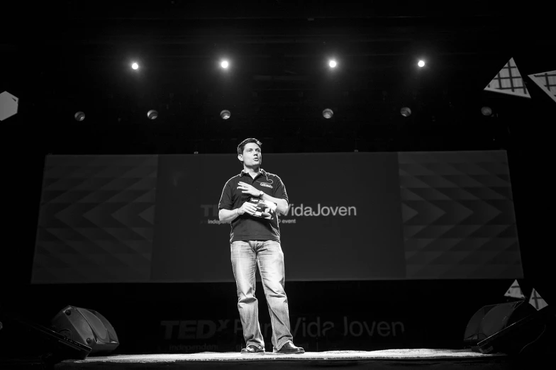 a man is standing on a stage in front of a black background