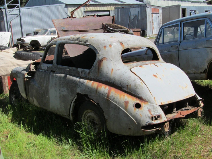 old cars are scattered across the field, one rusty