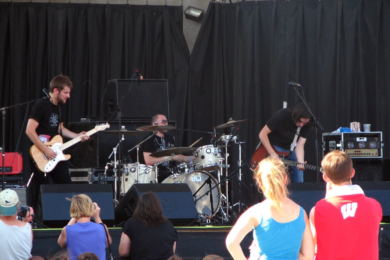 a band with musical instruments on stage with an audience watching