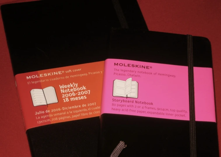 the small notebook is black with pink and orange pages