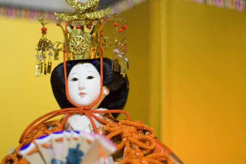 an oriental doll wearing a tiara and holding cards