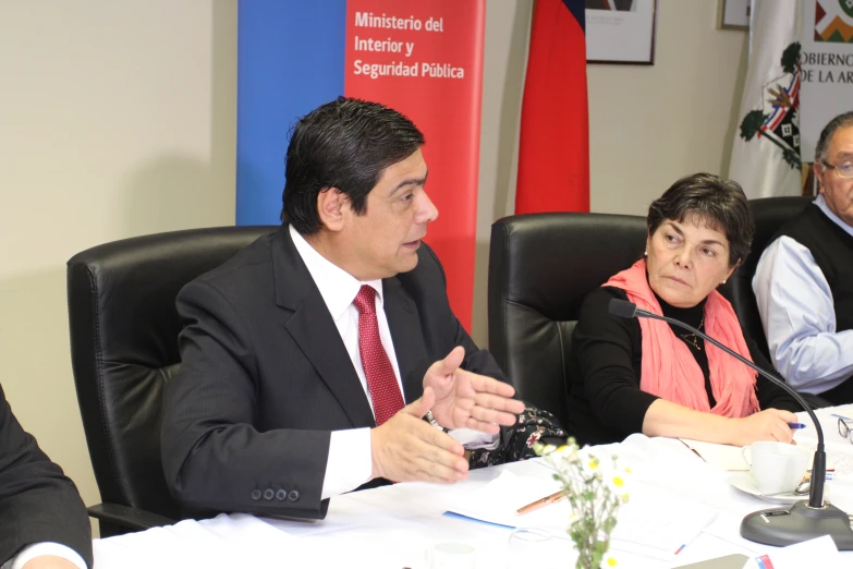 three people are sitting at a conference table