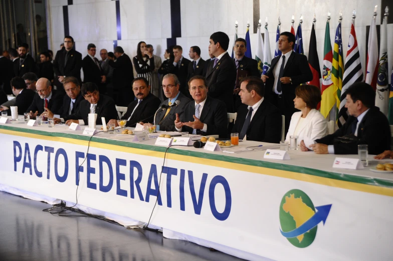 several people sitting at tables with flags behind them