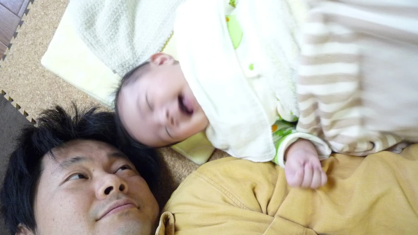 a man sleeping with a baby under a blanket