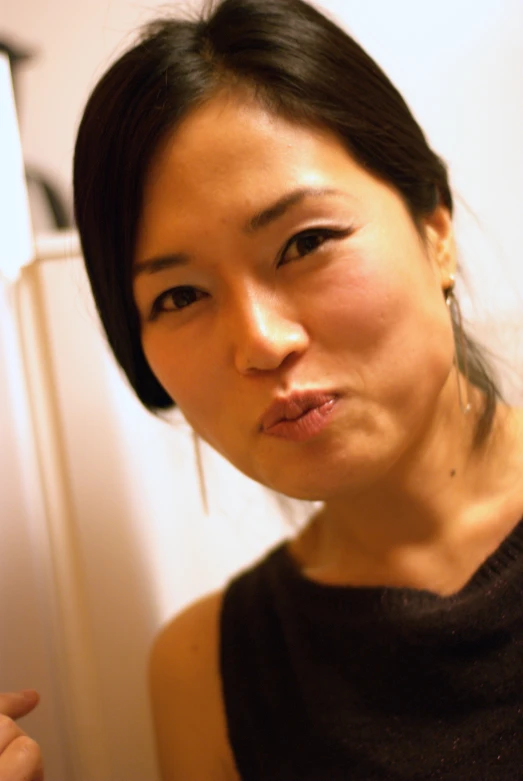 an asian woman in front of refrigerator with soing in her hand