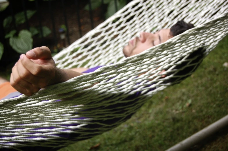 a person laying in a hammock on top of grass