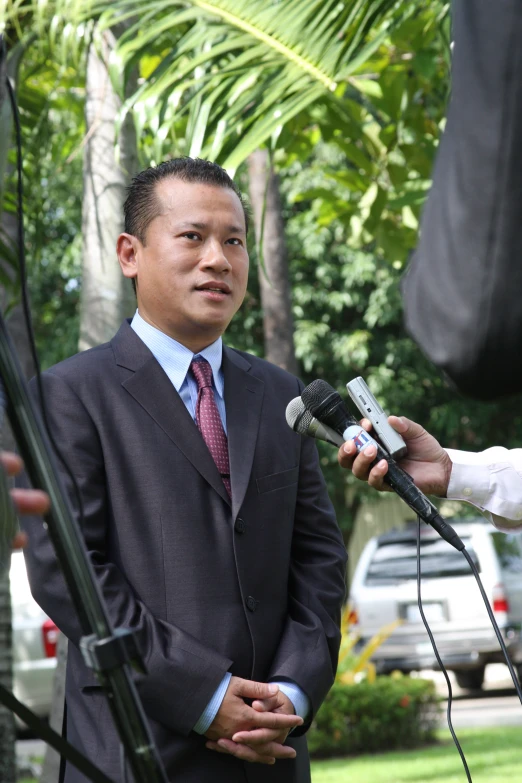 a man with microphone giving a talk at an outdoor ceremony