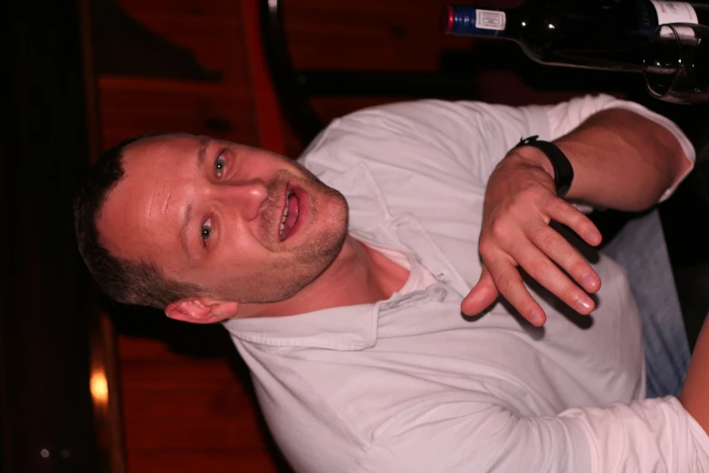 man in white shirt at a table with a bottle