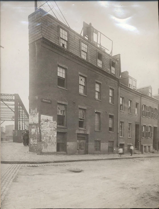 an old po of an apartment building on the corner of a street