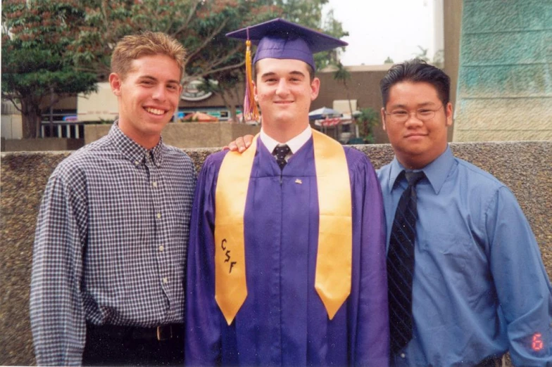 three guys in their graduation regalies are posing for the camera