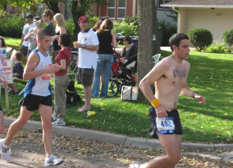 two shirtless men run in front of an audience