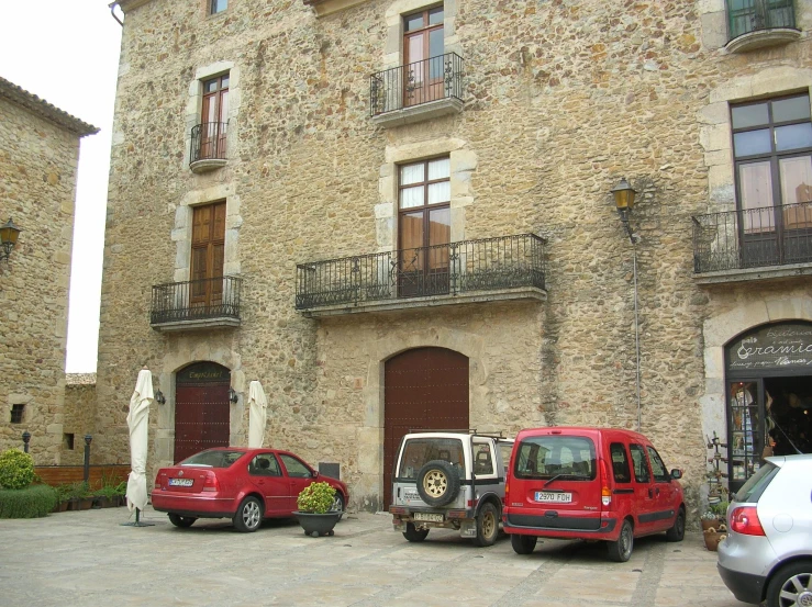 three cars in front of an old stone building