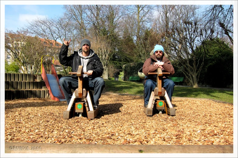 two men sitting on wooden seats in the grass