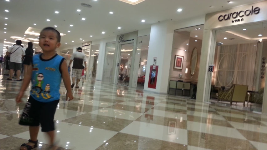 the little boy is walking around inside the mall