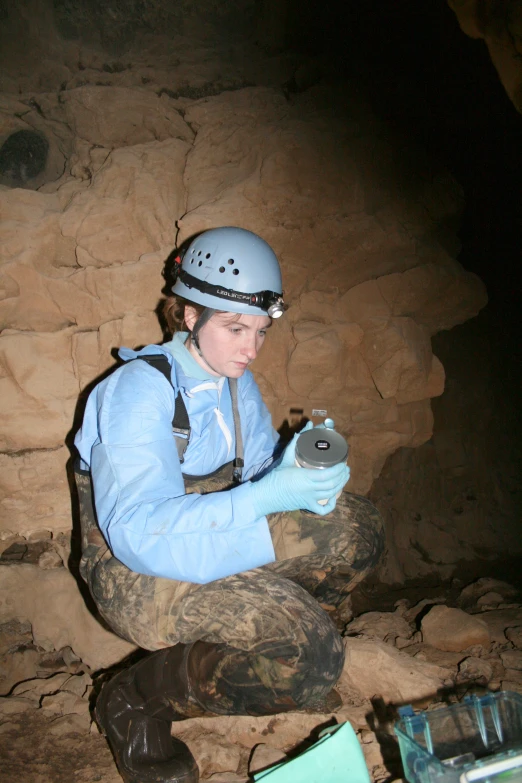 a woman sitting on top of some rocks wearing a helmet