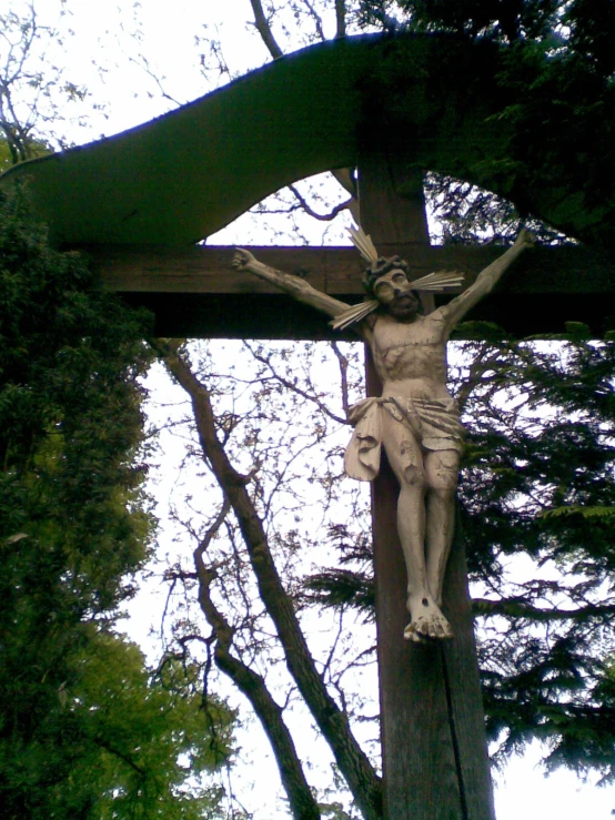 a crucifix is displayed in front of a bunch of trees