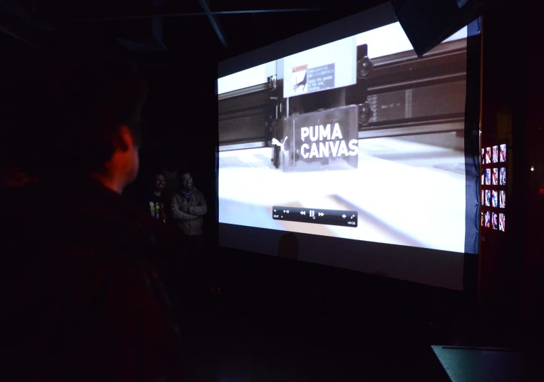 a man standing in front of a big screen with some writing on it