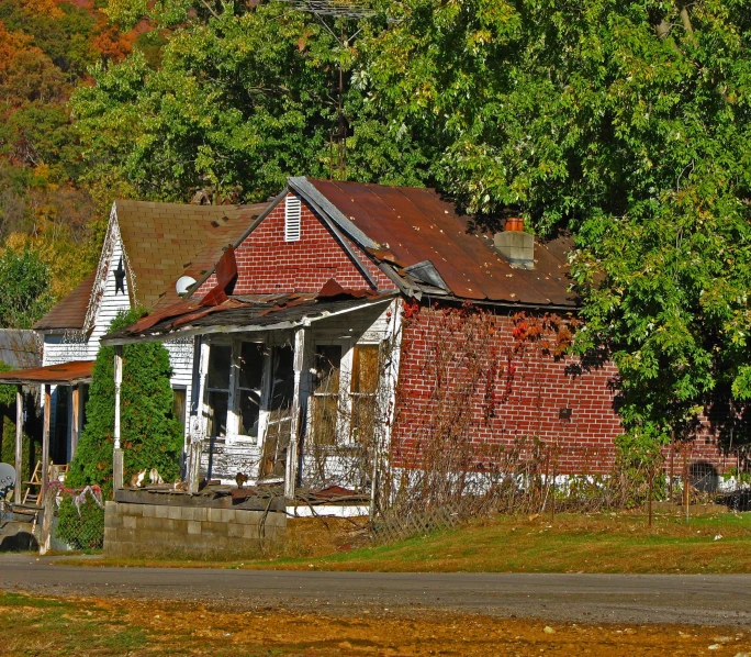 a run down red brick house next to a green field