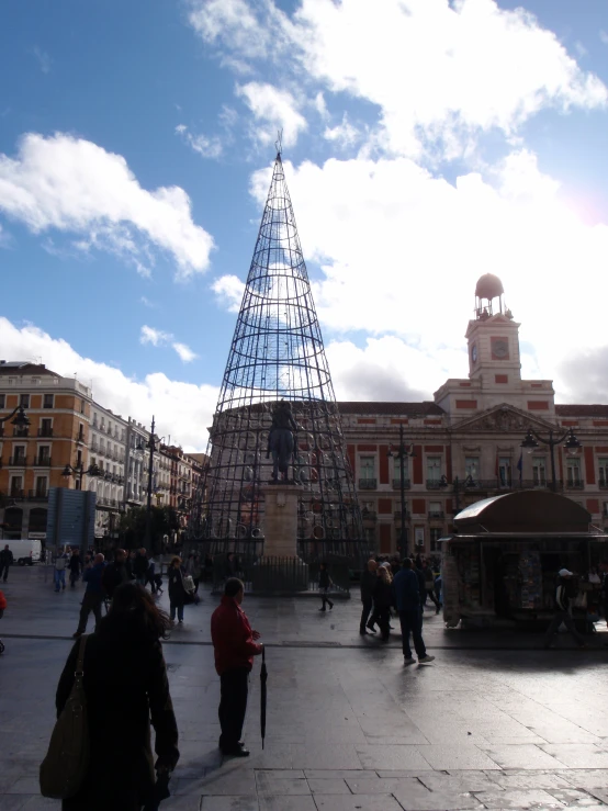 people on the sidewalk near a tower like structure