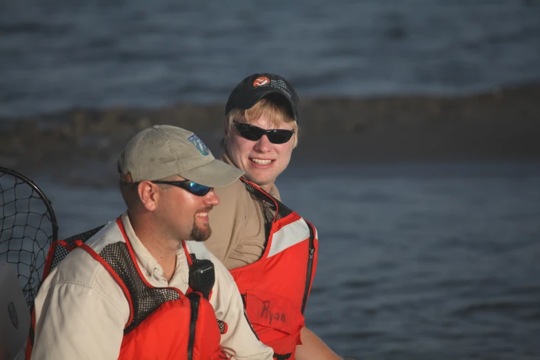 a smiling man in an life jacket and sunglasses holding onto a woman