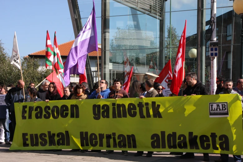 the group of people are standing by a sign with flags