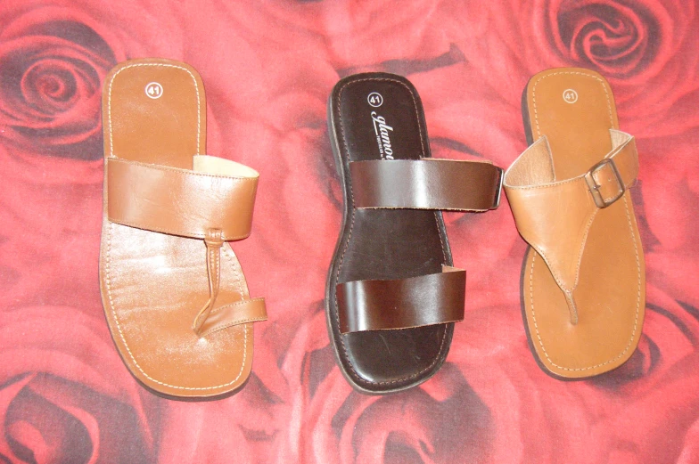 three different sandals in different colors sitting on a bed