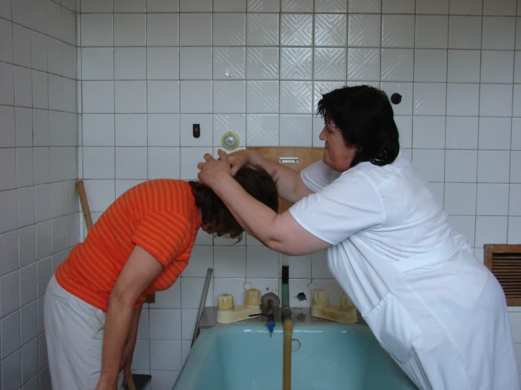 a woman and a girl are doing hair tasks in the bathroom