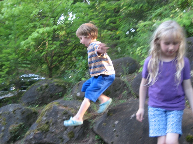 two s playing in a rocky area outside