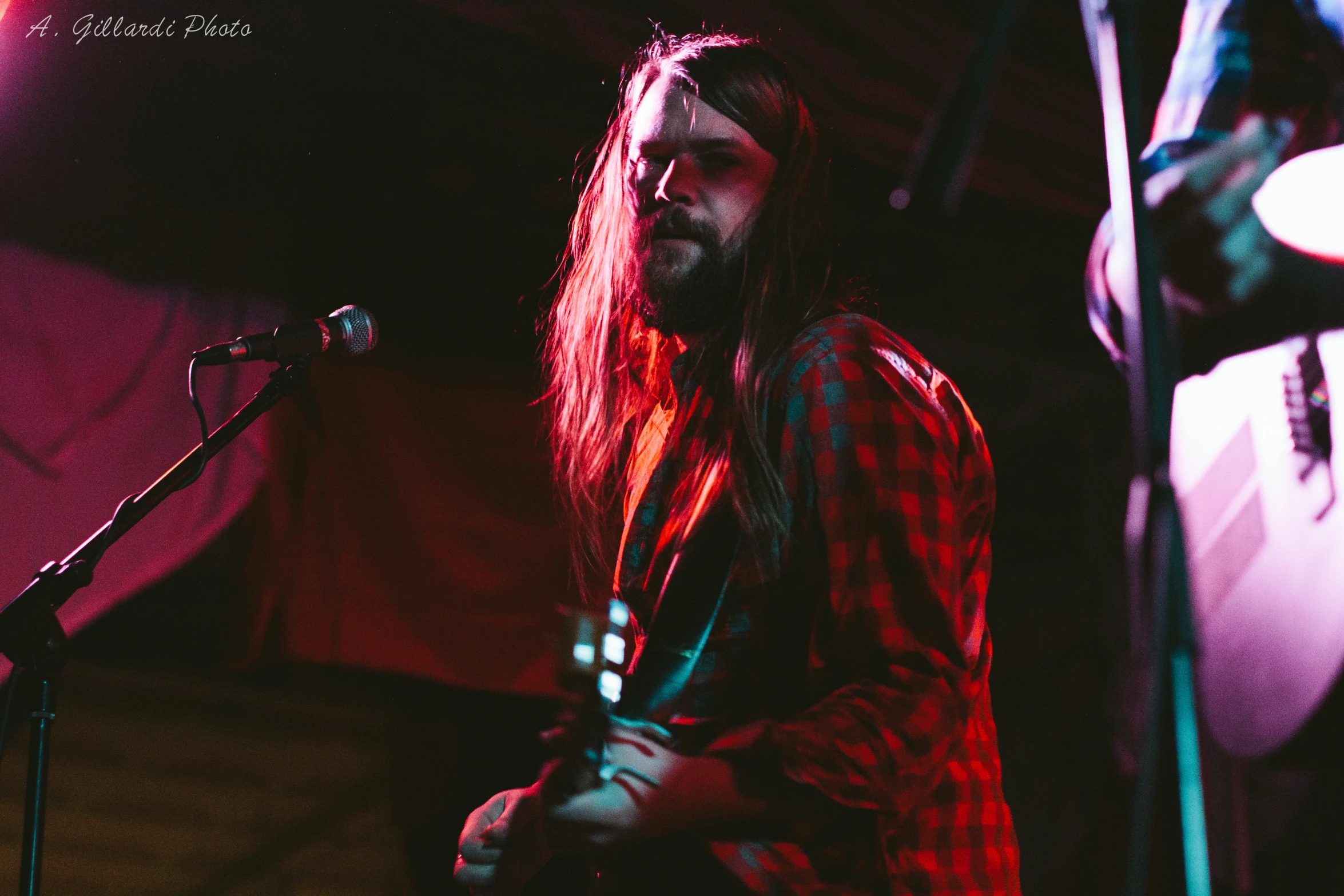 the man is playing a guitar in front of the microphone