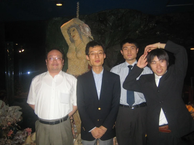 four people pose together in front of a statue