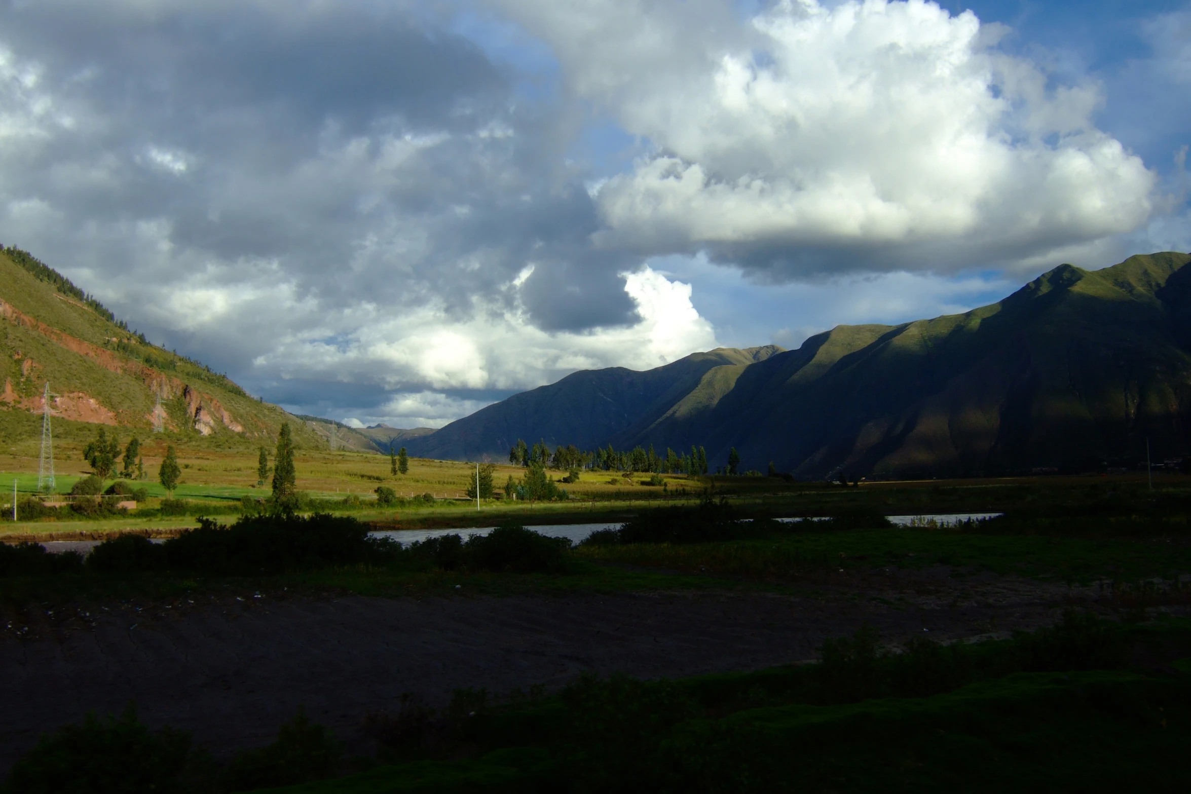 green grassy mountains and a river surrounded by a forest