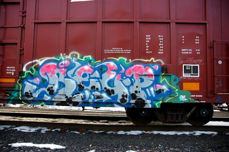 a train car sitting in front of some graffiti