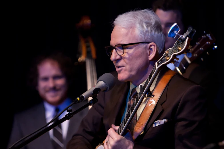 a man with glasses playing an acoustic guitar