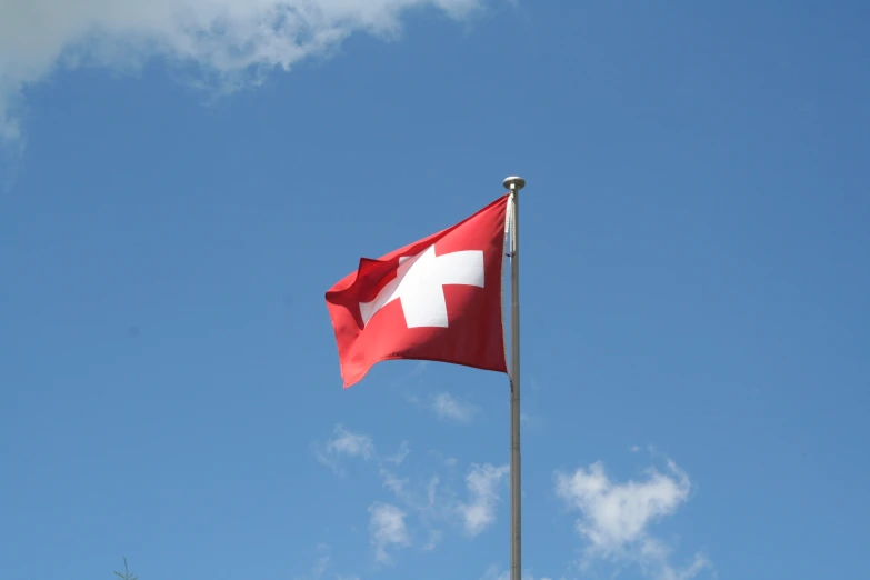 a swiss flag with a white cross on it flying in the air