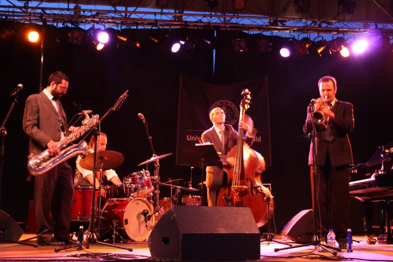 a band on stage playing musical instruments on a dark background