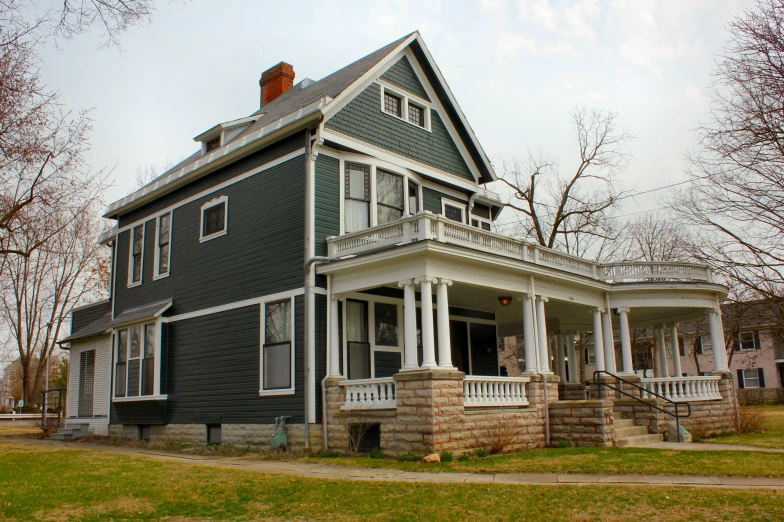 this victorian house is near some dead trees